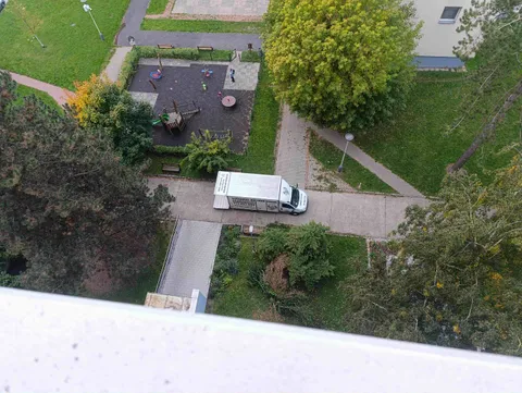 Stěhováci přenášejí skříň po schodech v panelovém domě