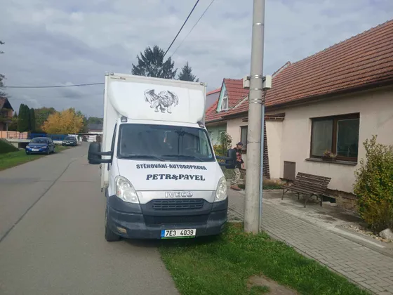 Dva stěhováci přenášejí skříň při stěhování bytu