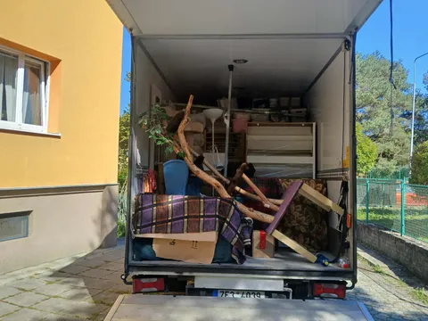 Naložený stěhovací vůz před panelovým domem během stěhování bytu