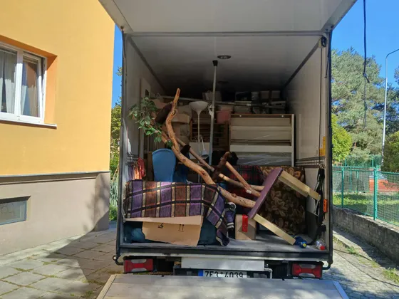 Naložený stěhovací vůz před panelovým domem během stěhování bytu