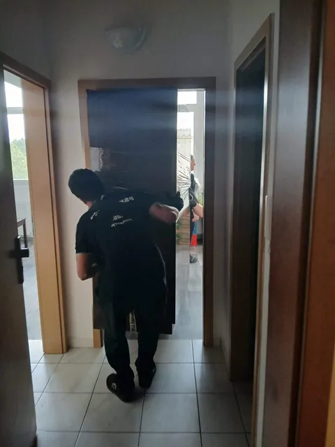 Stěhovák přenáší věci chodbou bytového domu