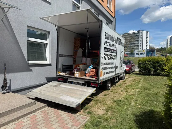 Stěhovací vůz se spuštěným hydraulickým čelem u bytového domu