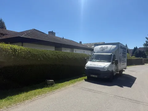 Stěhovací vůz u rodinného domu se živým plotem