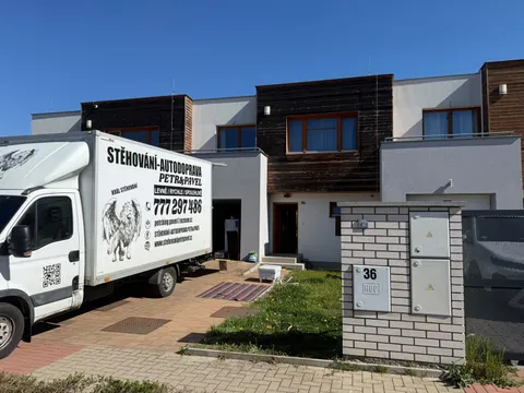 Stěhovací vůz zaparkovaný u moderního rodinného domu