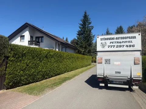 Stěhovací vůz přistavený za živým plotem